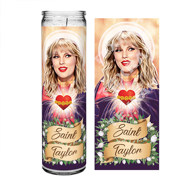 Saint Taylor Swift prayer candle design featuring an illustration of Taylor as a saint. She has blonde hair with bangs, a bright halo, and holds a radiant heart. The banner below reads 'Saint Taylor,' surrounded by green leaves and white flowers, with a warm, glowing background.